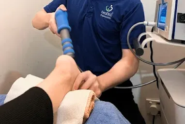 Physiotherapist using a treatment device around a patient's knee.