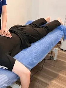 Physiotherapist providing hands-on treatment while a patient lies on a treatment table.