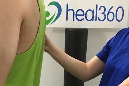 Physiotherapist assessing a patient's standing posture and movement.