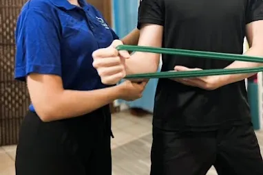 Physiotherapist guiding a patient through a resistance-band exercise.
